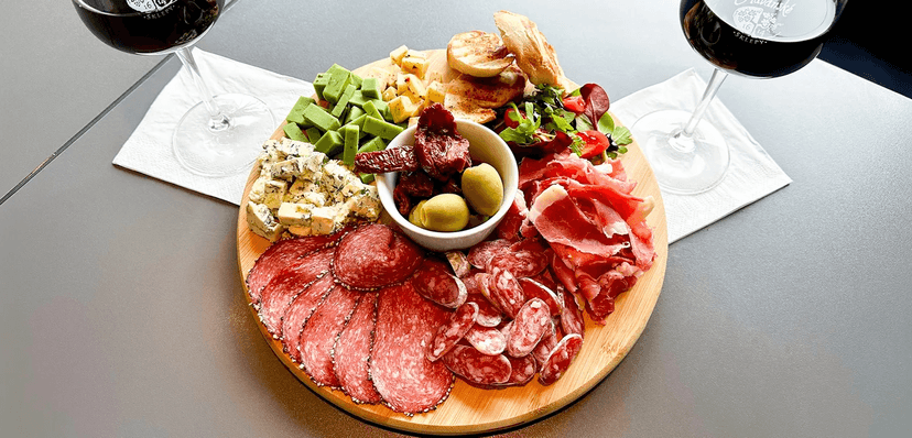 Degustační prkno pro 2⁠–⁠4 osoby: sýry, uzeniny, salátek, česneková bageta a červené víno k tomu 