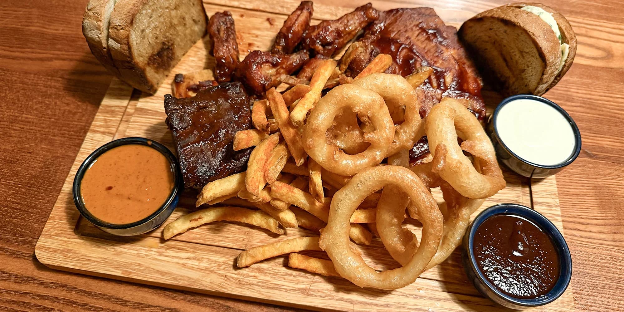 Hostina pro milovníky masa: prkno plné žeber a křídel, hranolky i cibulové kroužky